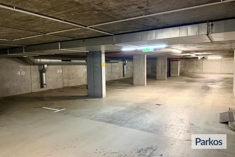 Unterirdische Parkgarage mit Betonpfeilern, markierten Stellplatznummern 36–40, Lüftungsrohr und Fluchtwegschild.