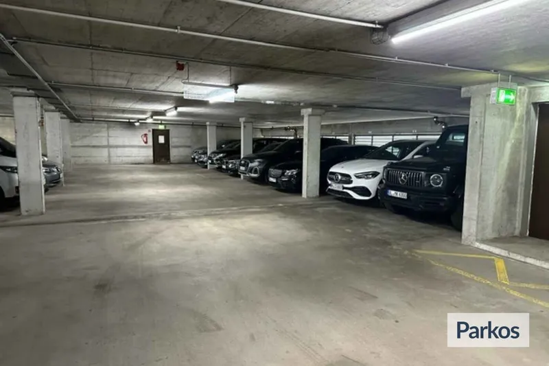 Überdachte Tiefgarage mit Stützpfeilern und einer Reihe geparkter Fahrzeuge rechts.