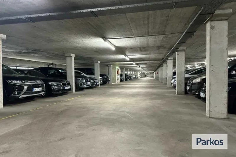 Überdachte Tiefgarage mit Reihen geparkter Autos und Betonstützen, Blick in die Fahrgasse.