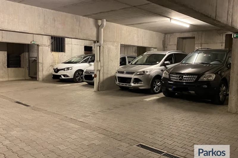 Überdachte Tiefgarage mit vier geparkten Pkw, Betonstützen und Deckenlampen.
