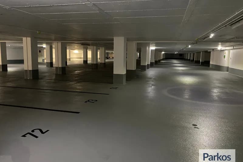 Überdachtes Parkgeschoss mit markierten Stellplätzen 72 und 73, Reihen von Säulen und Deckenbeleuchtung.