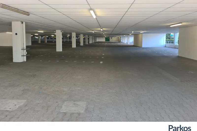 Überdachtes Parkdeck mit Stützpfeilern, Deckenbeleuchtung und Parkflächenmarkierungen.