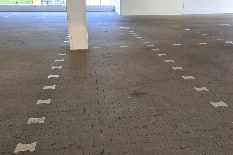 Überdachter leerer Parkplatz mit markierten Stellflächen und einem Stützpfeiler.