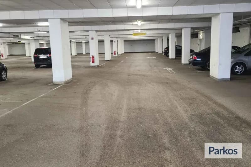 Überdachte Tiefgarage mit Reihen von Stützen, vereinzelt geparkten Autos und an Säulen angebrachten Feuerlöschern.