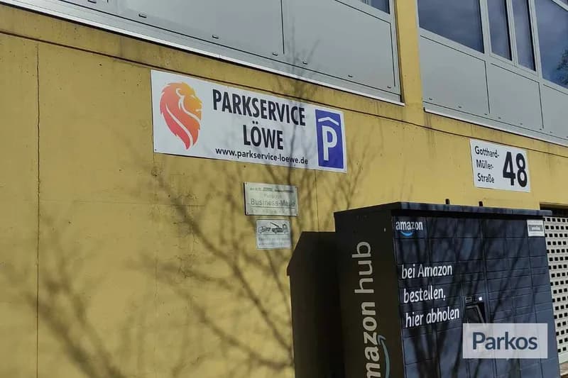 Gelbe Außenwand mit Parkservice Löwe Schild, Parksymbol, Hausnummer 48 und Amazon Hub Paketstation rechts.