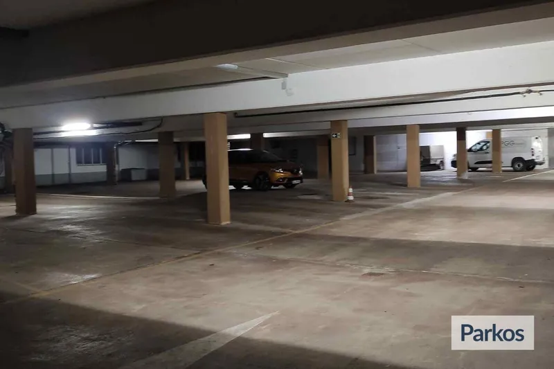 Überdachtes Parkdeck mit Stützsäulen, Bodenmarkierungen und zwei geparkten Fahrzeugen.
