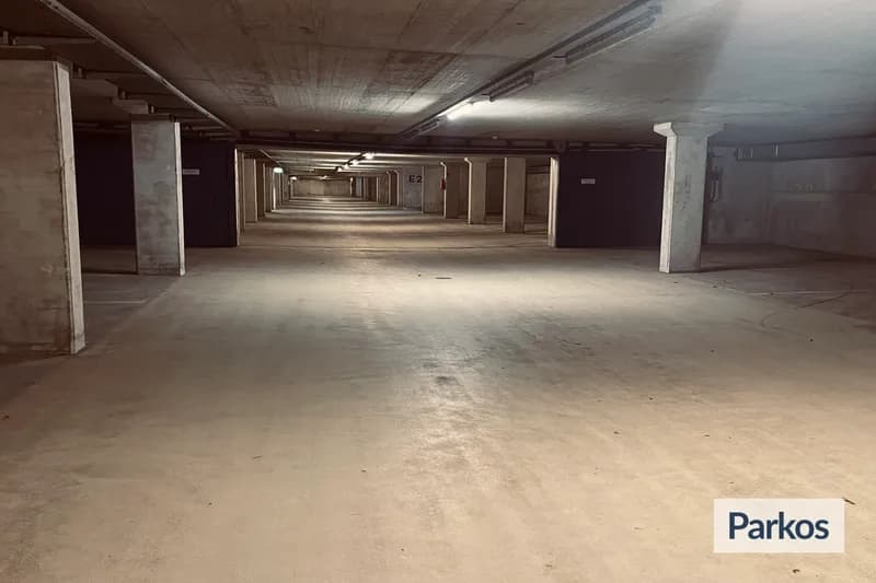 Leerer überdachter Parkdeckgang mit Betonpfeilern und Markierung E2, Parkos-Logo rechts unten.