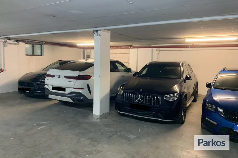 Überdachter Tiefgaragenstellplatz mit mehreren geparkten Autos und einer zentralen Säule; Parkos-Logo sichtbar.